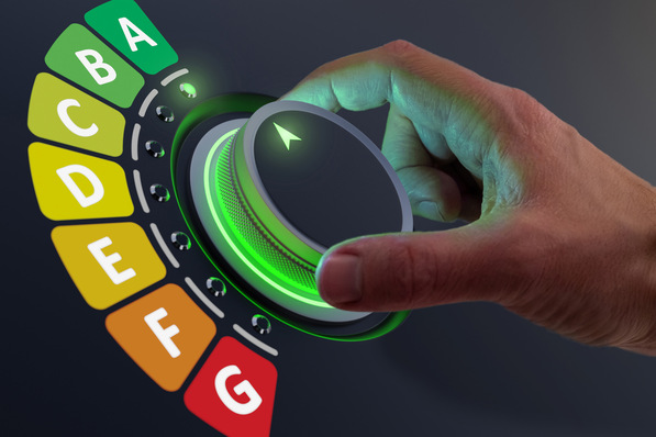 Hand stellt ein grün beleuchtetes Zifferblatt ein, das von Energieeffizienzklassen von A bis G umgeben ist. - © NicoElNino - stock.adobe.com