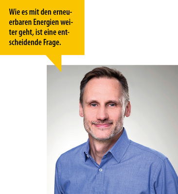 Lächelnder Mann im blauen Hemd mit einer Sprechblase auf Deutsch zum Thema erneuerbare Energien. - © Bild: privat