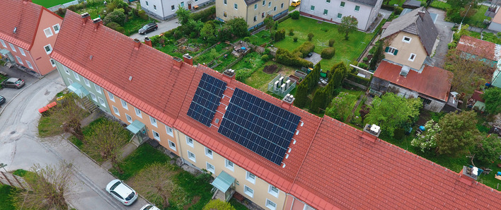 © Bild: GWS Das Happening-System, eine Kaskade aus Wärmepumpen, kommt in einem zusammenhängenden Riegel aus fünf Gebäuden in Liezen zum Einsatz. Heizzentrale und PV sind im beziehungsweise auf dem mittleren Gebäude installiert. Klein in weiß hinter dem Gebäude sind die Außeneinheiten der Luftwärmepumpen zu erkennen. Strombilanz und Anteil erneuerbarer Energien im Happening-System. Beim Happening-System liegen die Investitionskosten deutlich über dem Referenzsystem. Nach etwa 13 Jahren haben sich diese amortisiert.