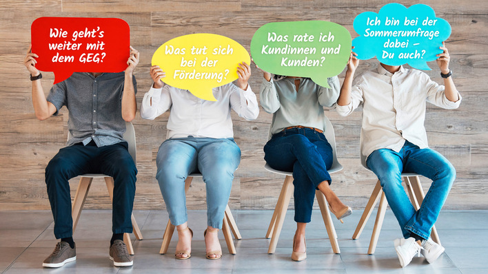 Vier Menschen sitzen auf Stühlen und halten bunte Schilder mit deutscher Aufschrift vor ihre Gesichter. - © Bild: Charlize D/peopleimages.com - stock.adobe.com
