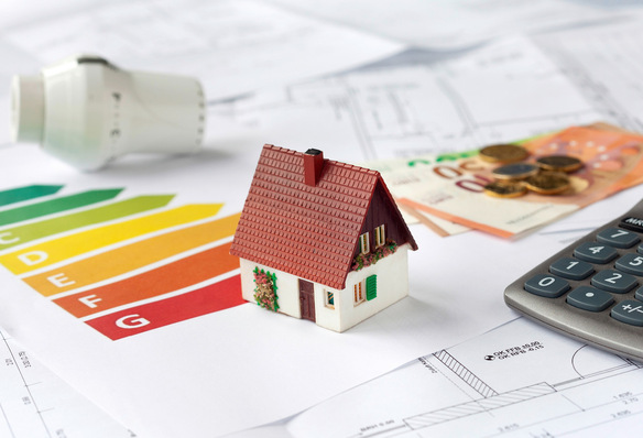 Ein kleines Hausmodell, eine Tabelle zur Energiebewertung, Euros und ein Rechner für Architekturpläne. - © Bild: USeePhoto - stock.adobe.com